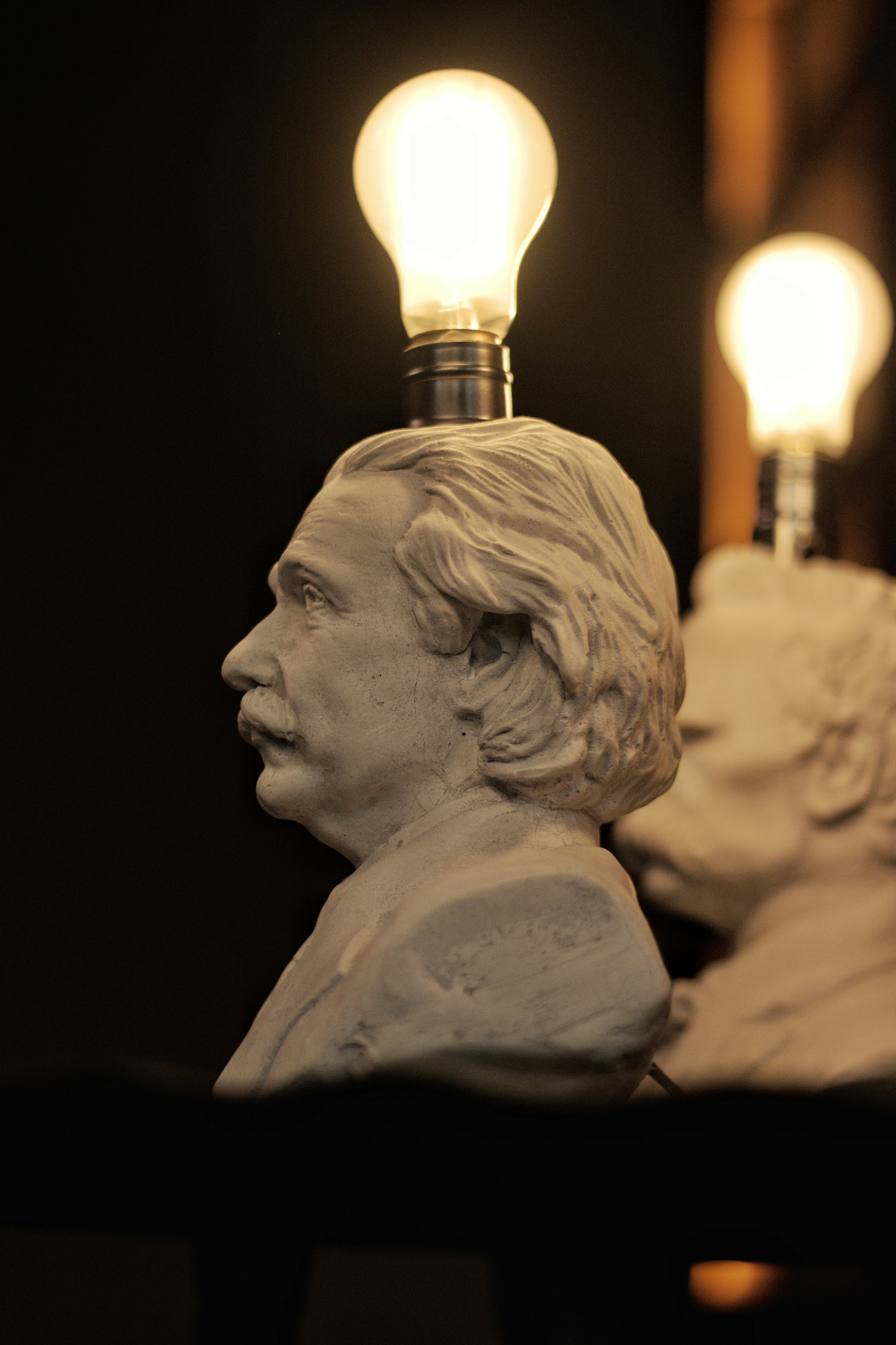 Busts with light bulbs on heads against a dark background